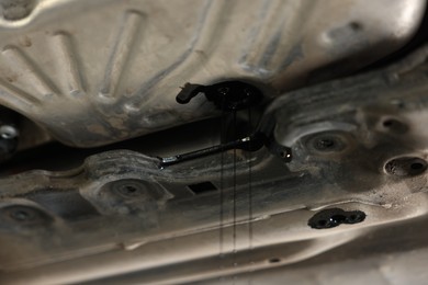 Photo of Dirty old motor oil dripping from car engine in workshop, closeup