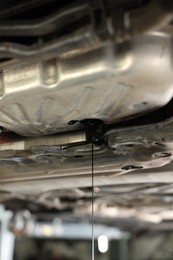 Photo of Dirty old motor oil dripping from car engine in workshop, closeup