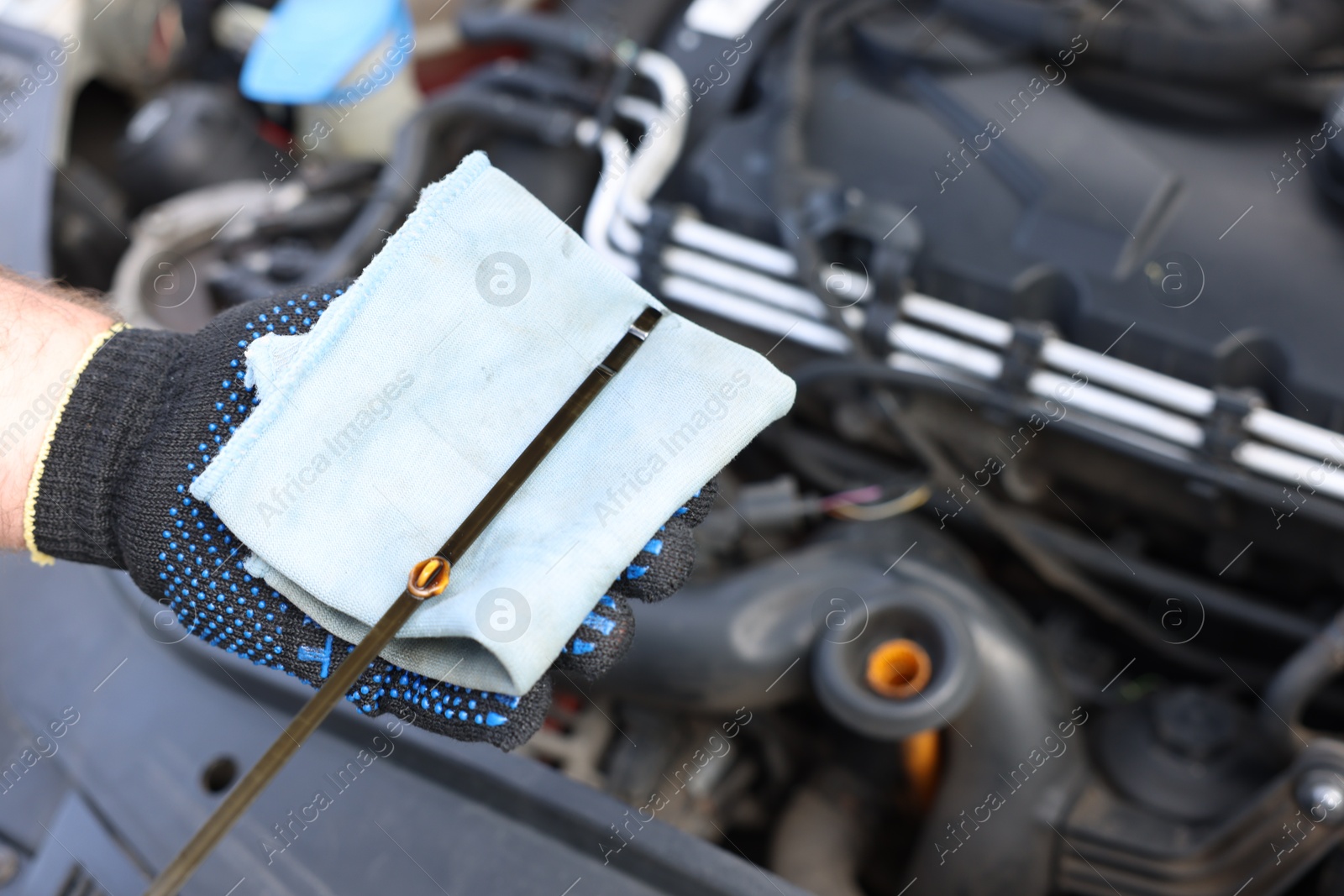Photo of Worker checking motor oil level in car with dipstick, closeup
