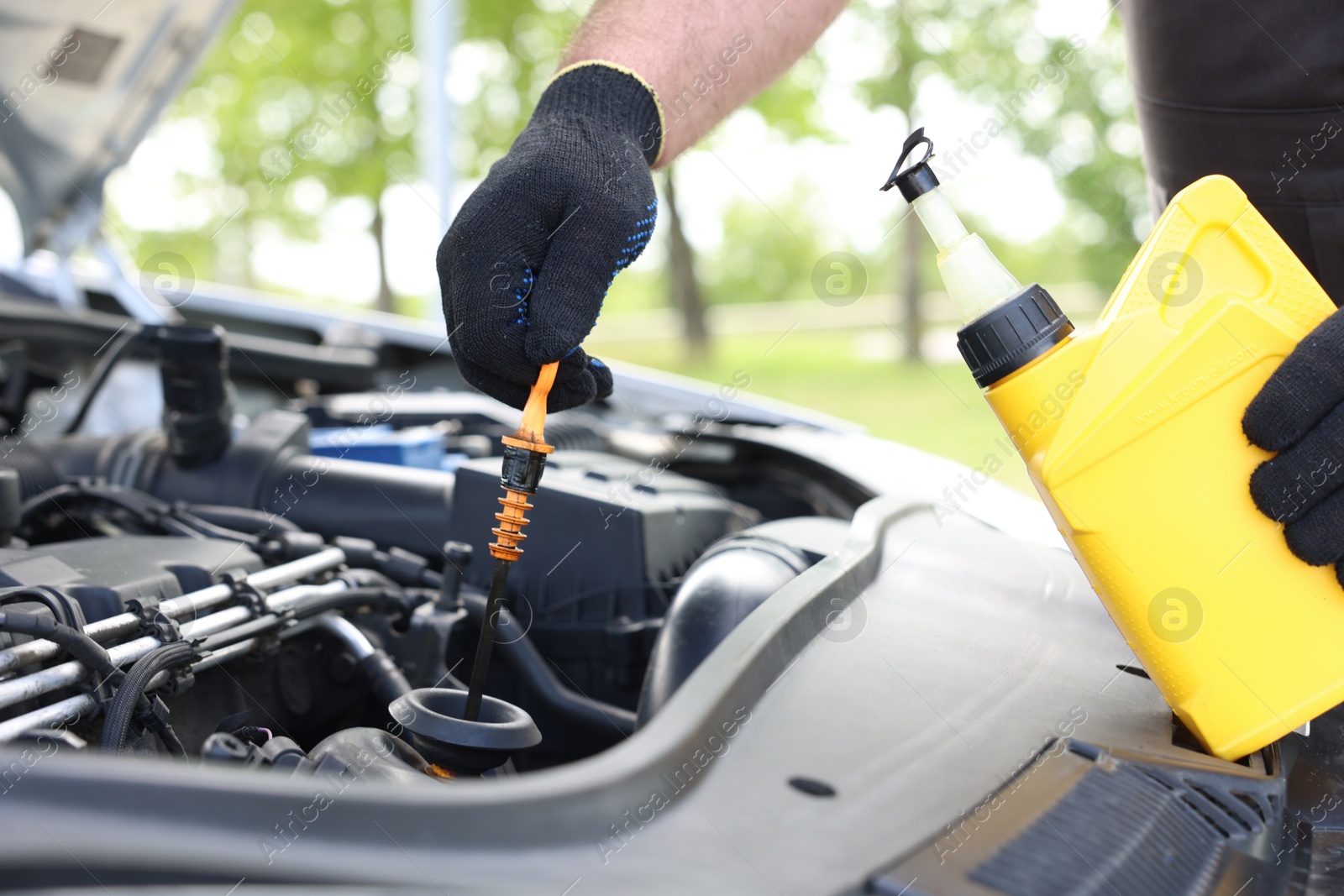 Photo of Worker checking motor oil level in car with dipstick, closeup
