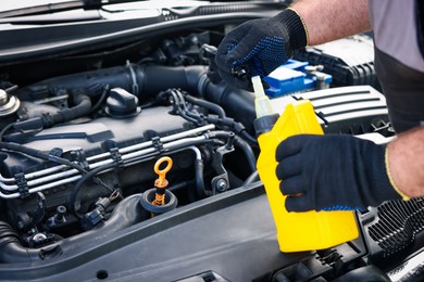Photo of Worker checking motor oil level in car with dipstick, closeup