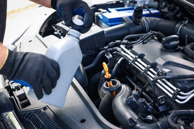 Photo of Worker checking motor oil level in car with dipstick, closeup