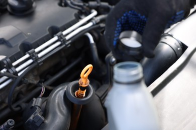 Photo of Worker checking motor oil level in car with dipstick, closeup