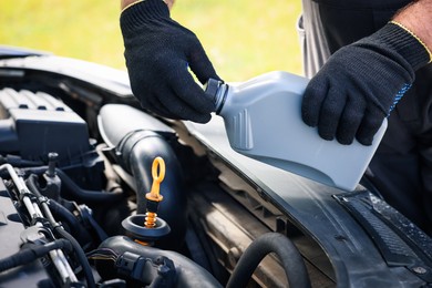 Photo of Worker checking motor oil level in car with dipstick, closeup