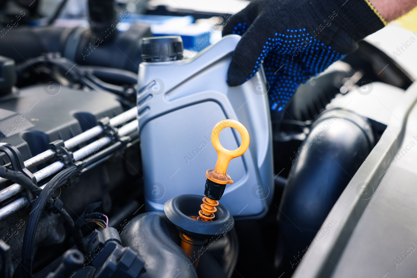 Photo of Worker checking motor oil level in car with dipstick, closeup