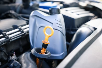 Photo of Checking motor oil level. Dipstick in car engine and bottle, closeup