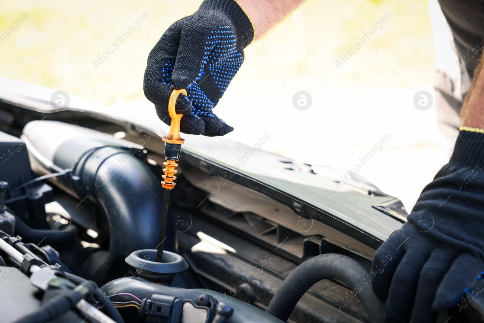 Worker checking motor oil level in car with dipstick, closeup Photo of Worker checking motor oil level in car with dipstick, closeup