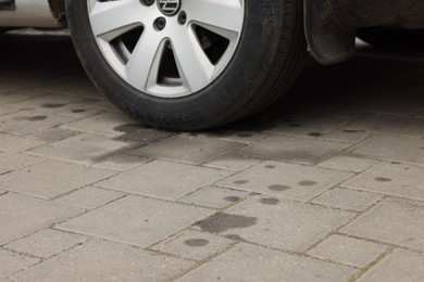 Photo of Stains of motor oil on road under car outdoors, closeup