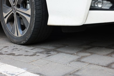 Photo of Stains of motor oil on road under car outdoors, closeup