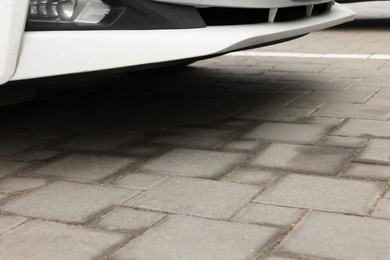 Photo of Stains of motor oil on road under car outdoors, closeup