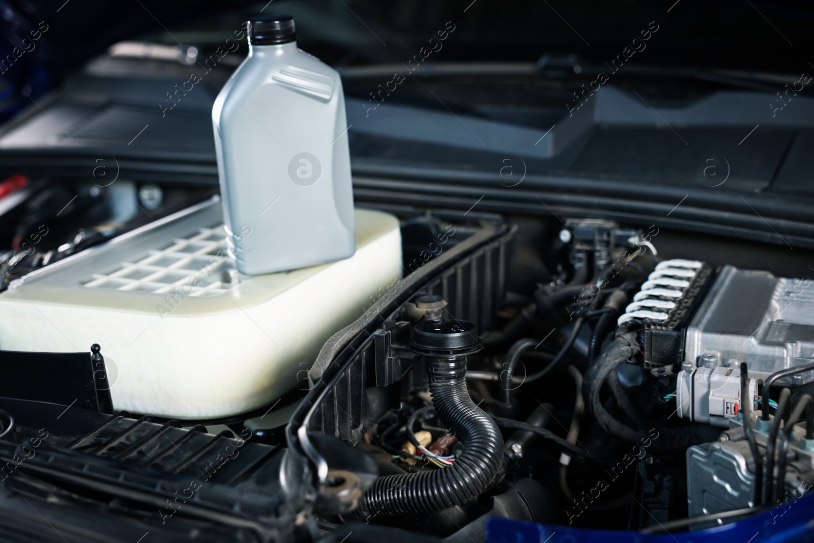Bottle of motor oil on car engine, closeup Photo of Bottle of motor oil on car engine, closeup