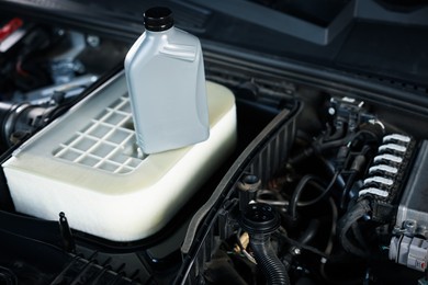 Photo of Bottle of motor oil on car engine, closeup