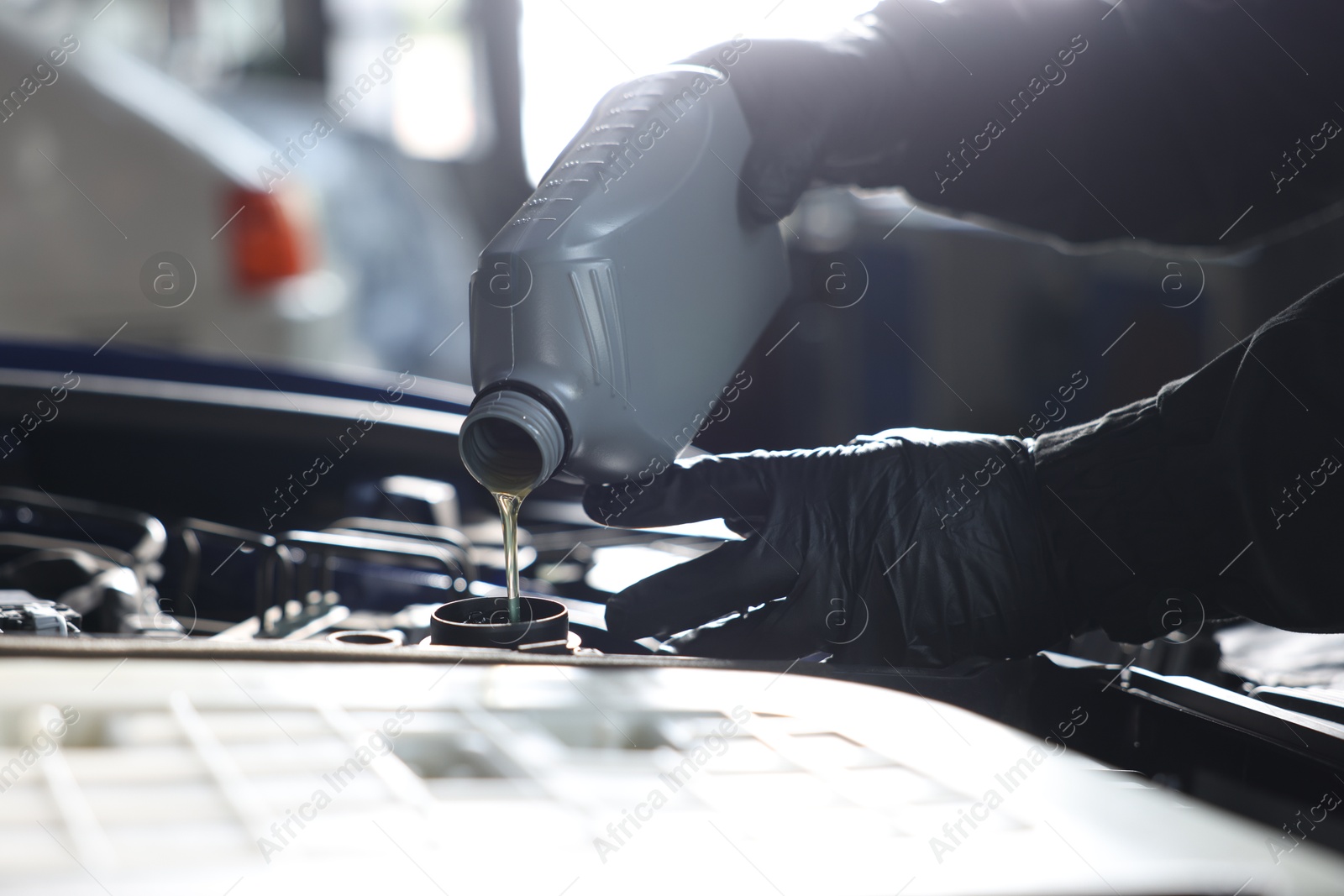 Worker pouring motor oil from canister into car engine, closeup Photo of Worker pouring motor oil from canister into car engine, closeup