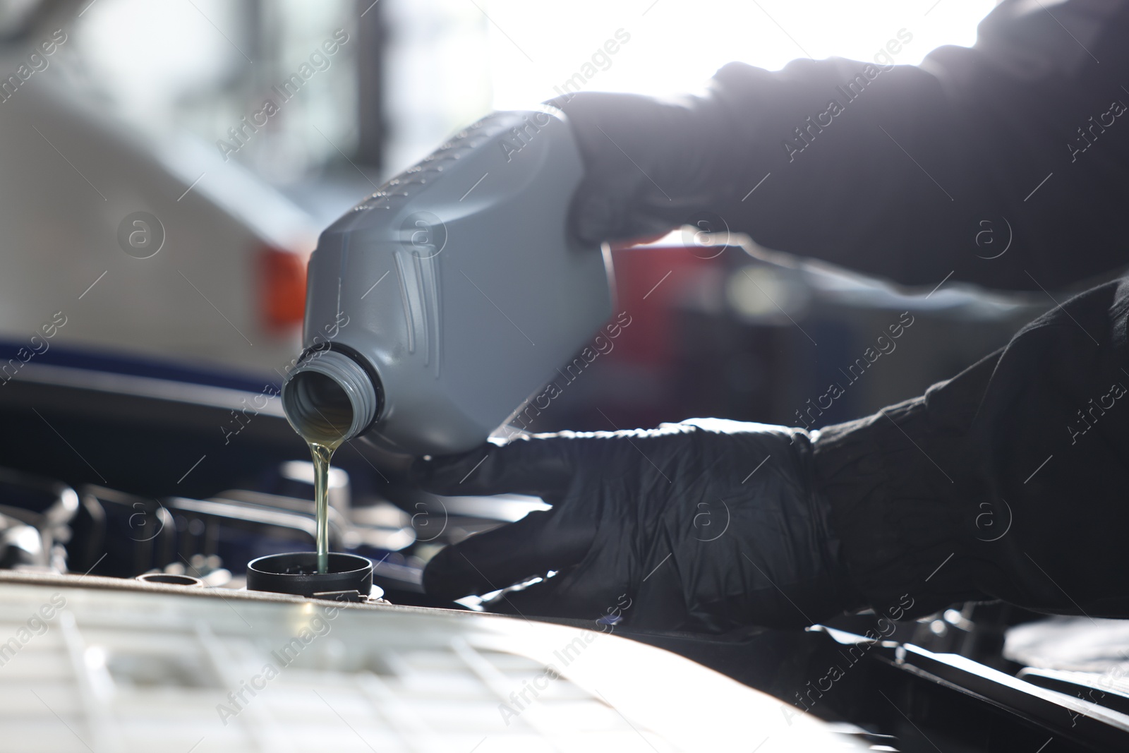 Worker pouring motor oil from canister into car engine, closeup Photo of Worker pouring motor oil from canister into car engine, closeup