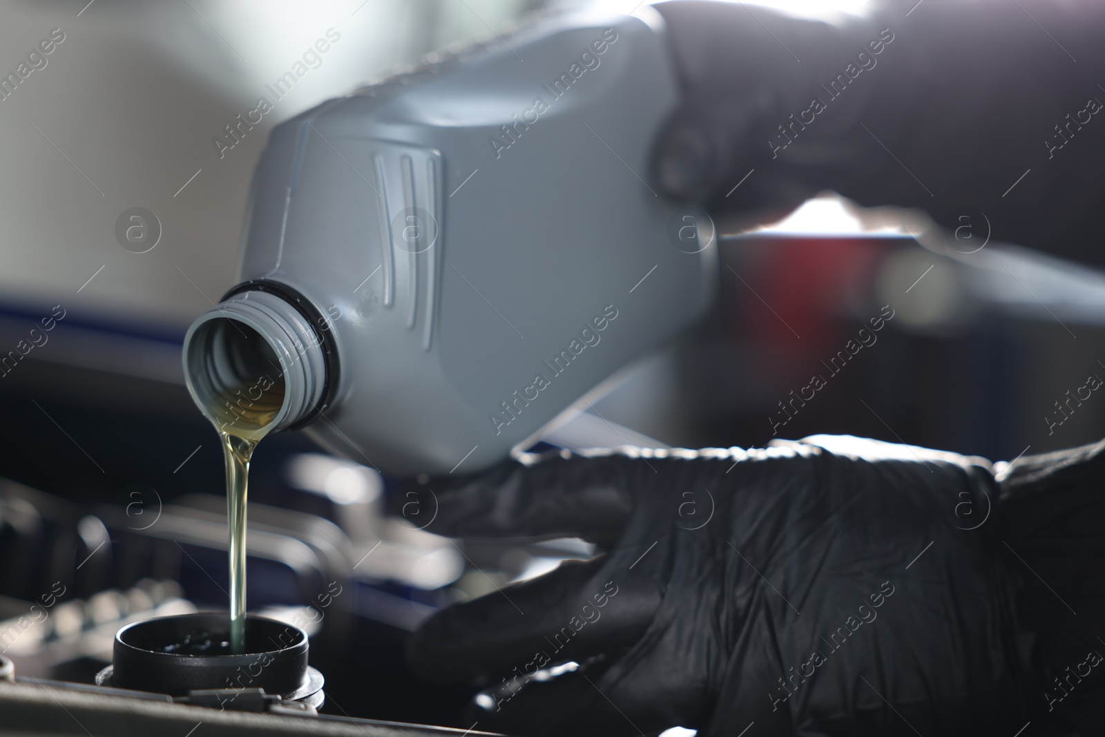 Worker pouring motor oil from canister into car engine, closeup Photo of Worker pouring motor oil from canister into car engine, closeup