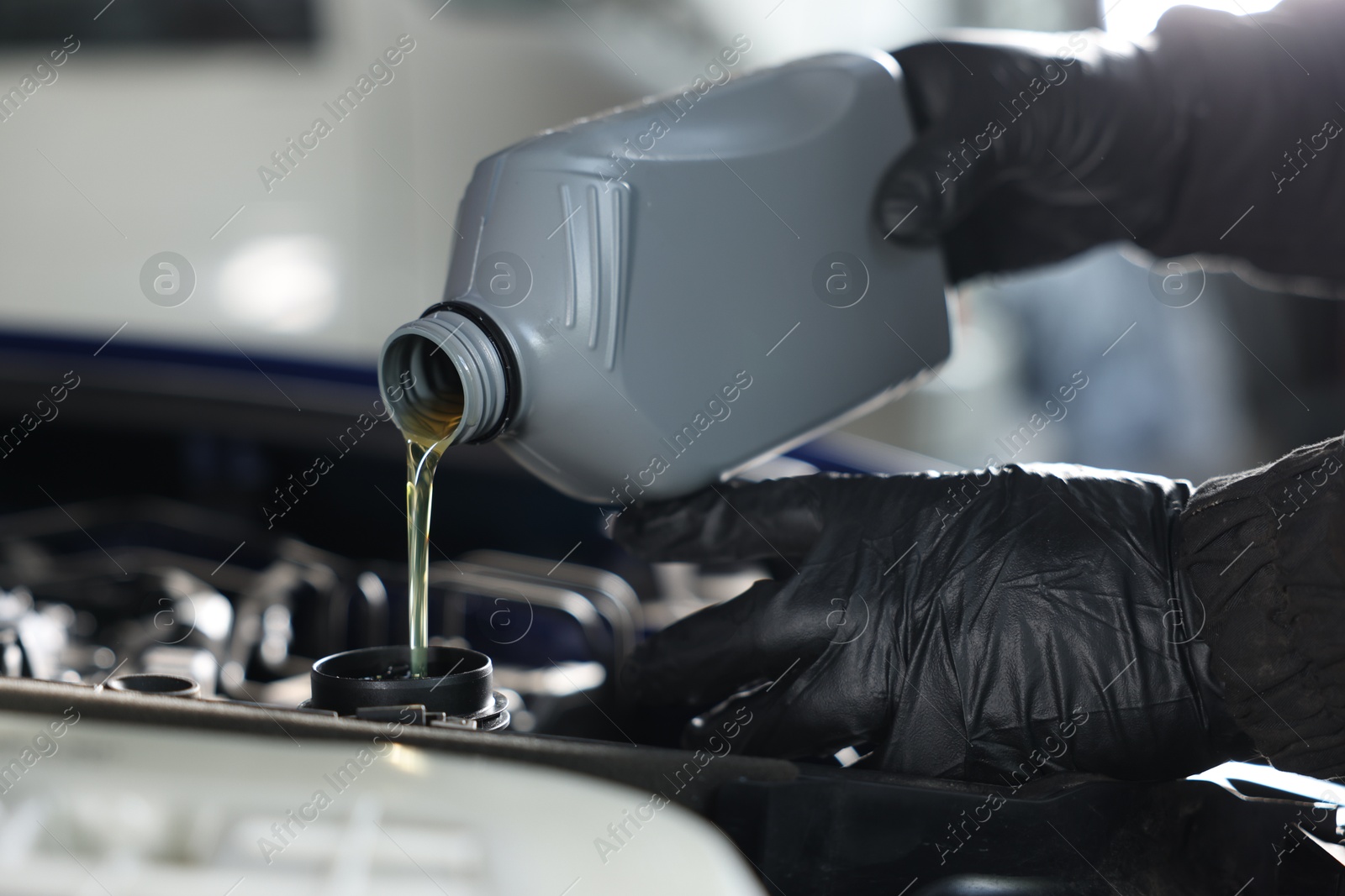 Worker pouring motor oil from canister into car engine, closeup Photo of Worker pouring motor oil from canister into car engine, closeup