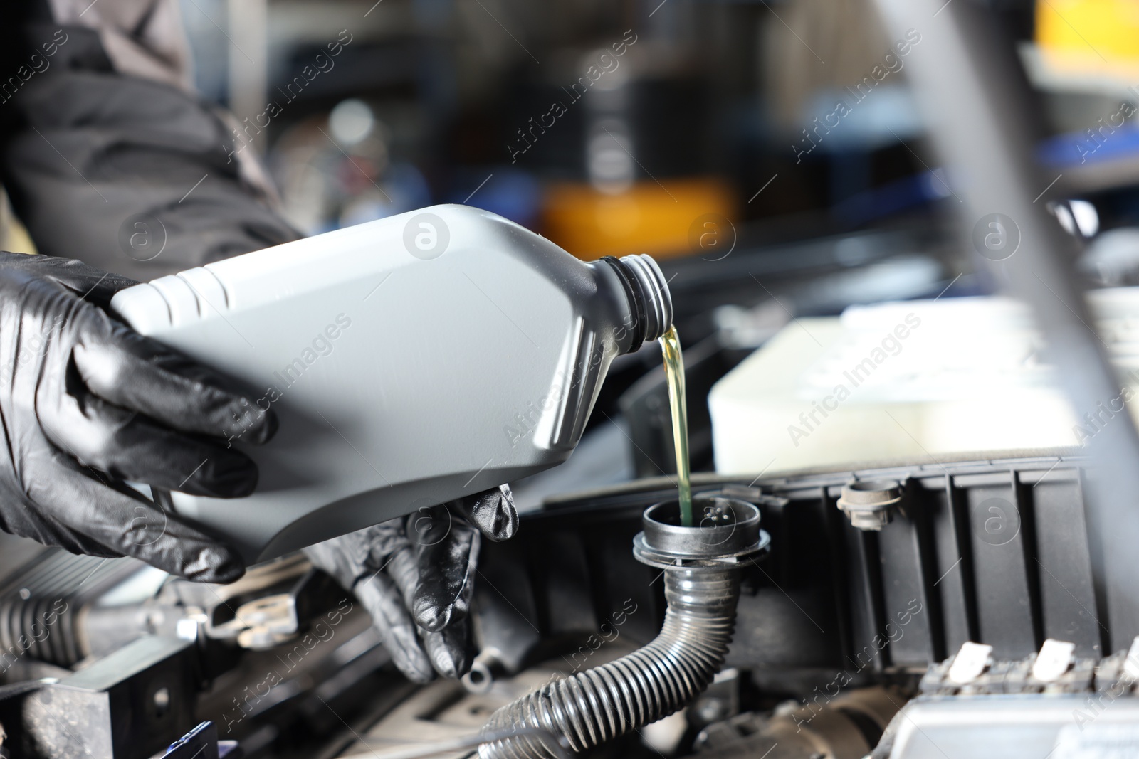 Worker pouring motor oil from canister into car engine, closeup Photo of Worker pouring motor oil from canister into car engine, closeup