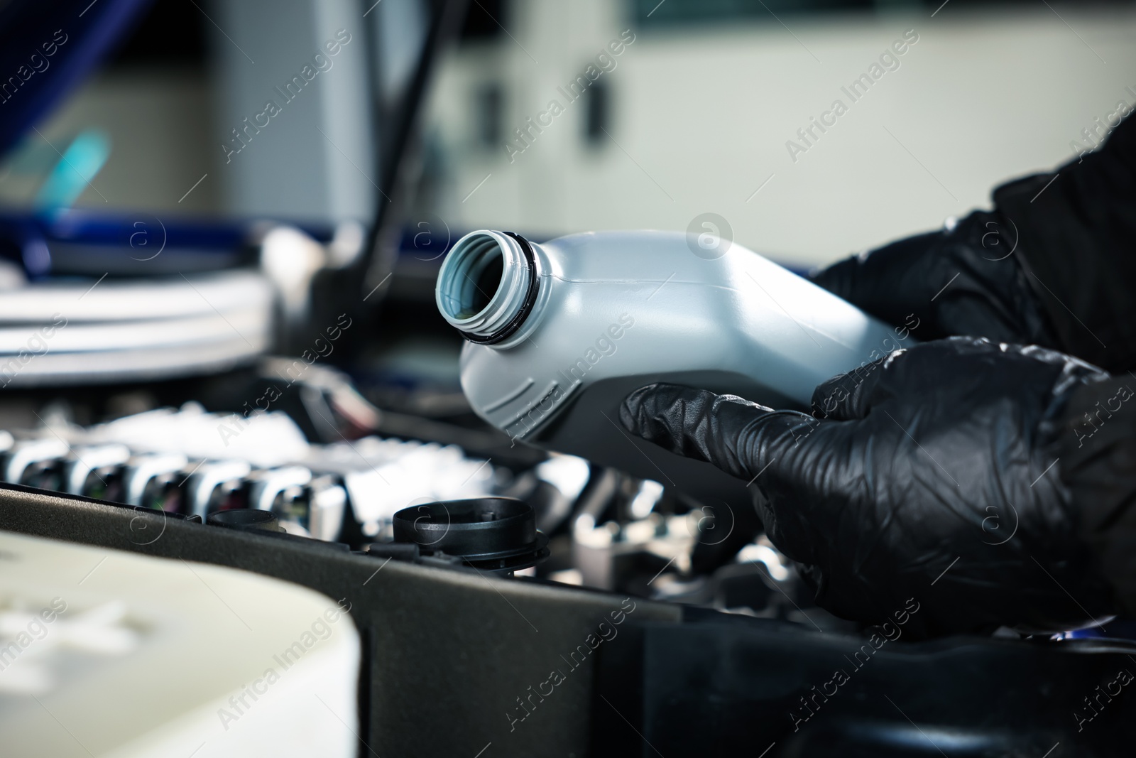 Worker pouring motor oil from canister into car engine, closeup Photo of Worker pouring motor oil from canister into car engine, closeup