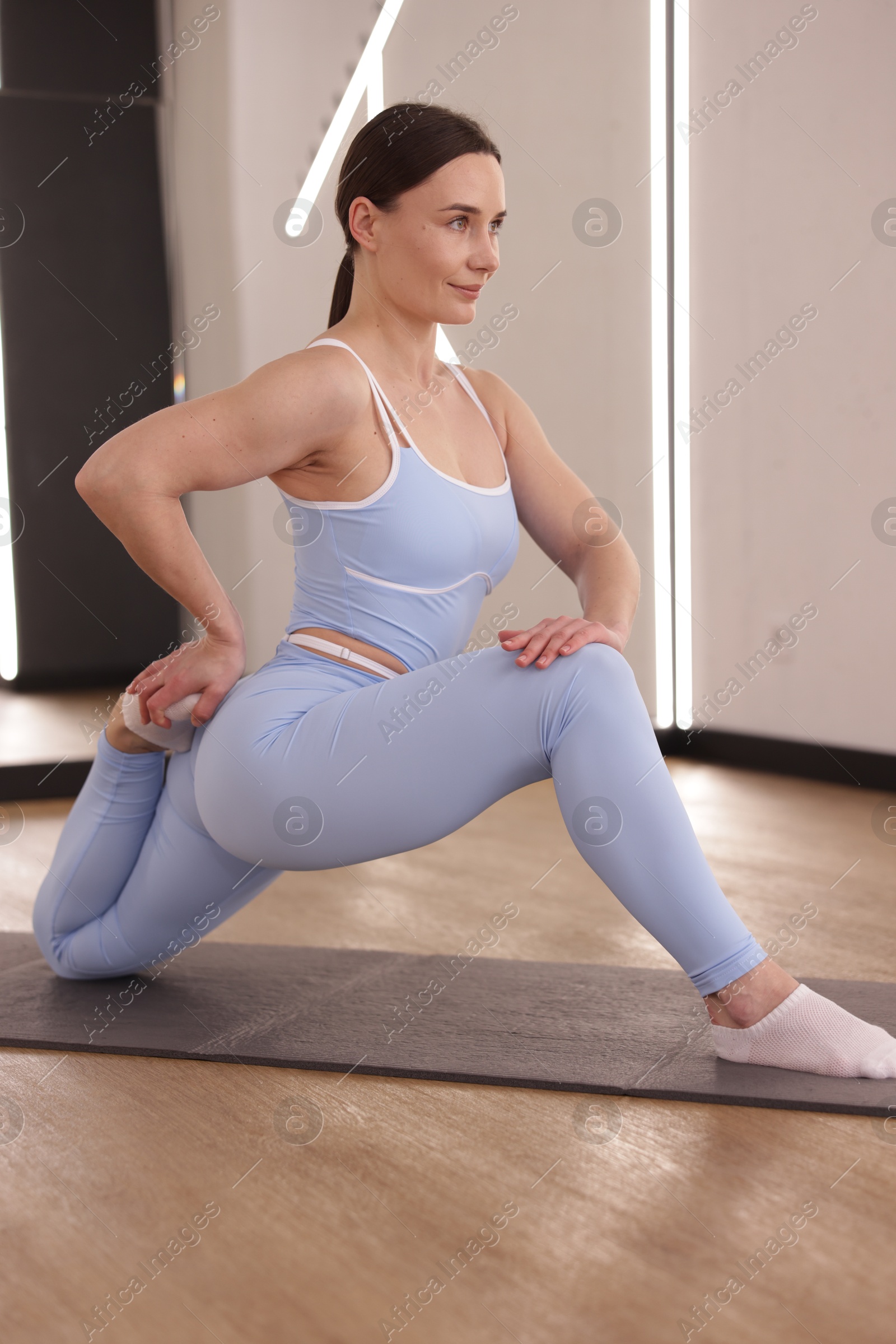 Woman stretching on mat in fitness studio Photo of Woman stretching on mat in fitness studio