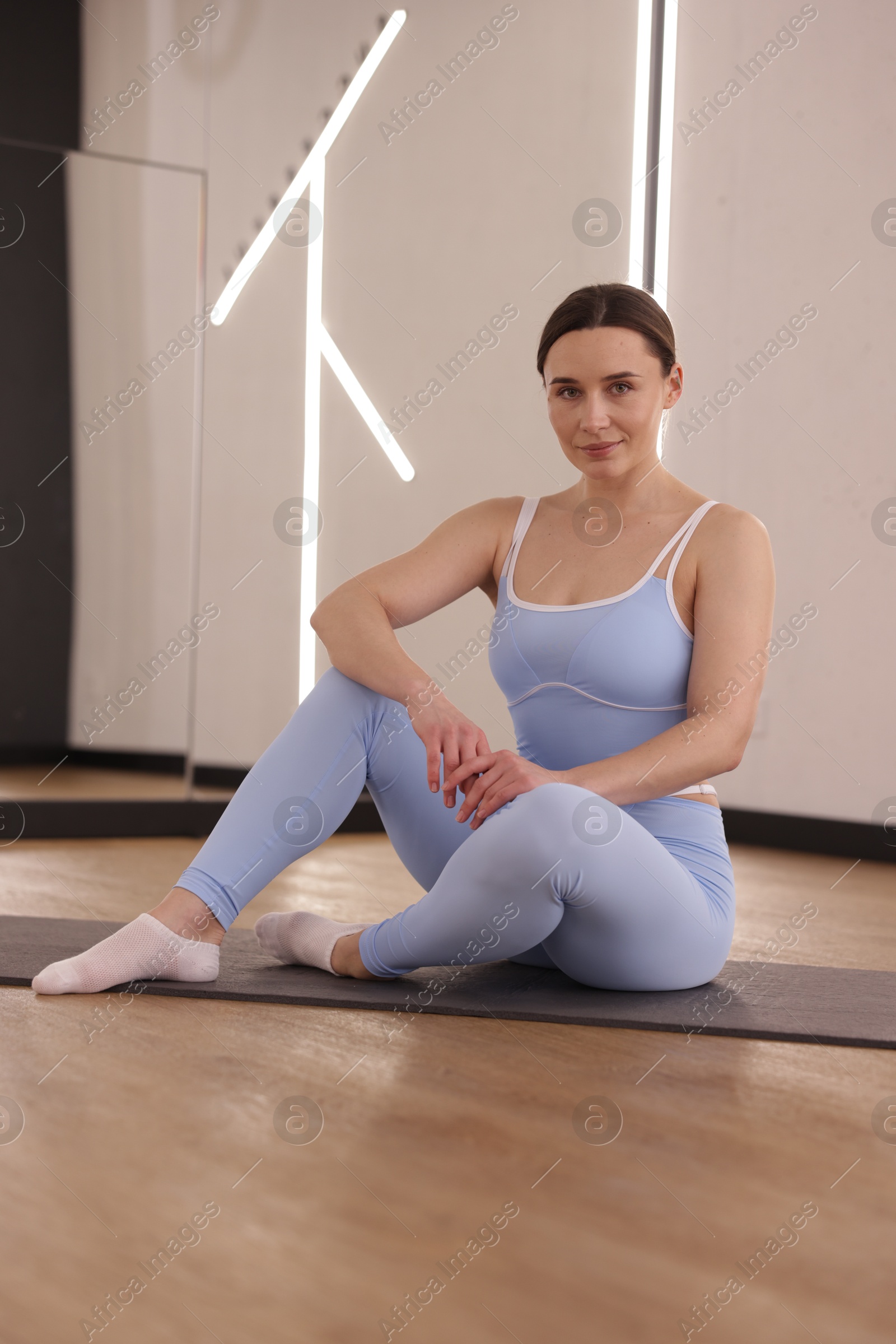 Photo of Woman wearing sportswear on mat in fitness studio