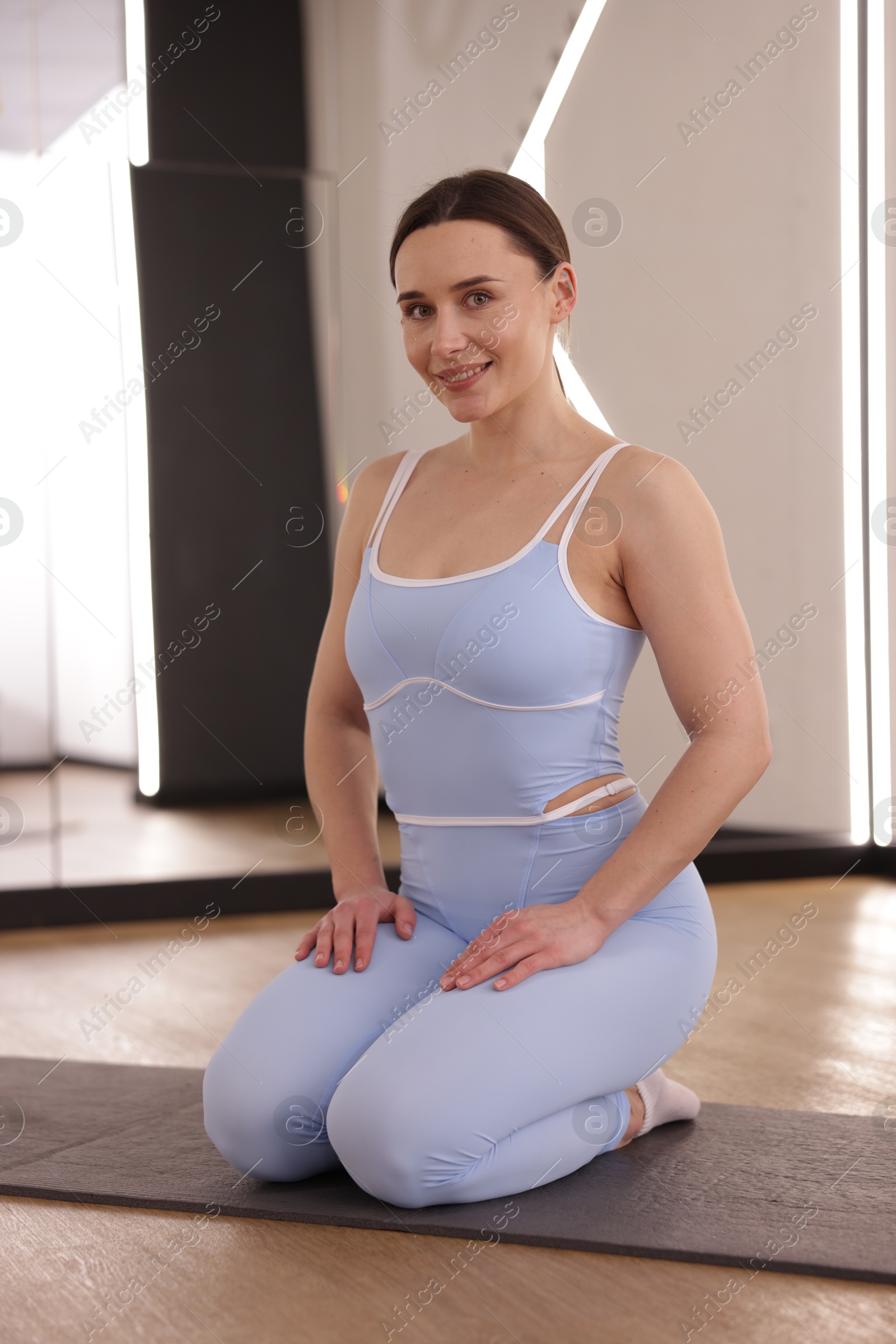 Photo of Woman wearing sportswear on mat in fitness studio