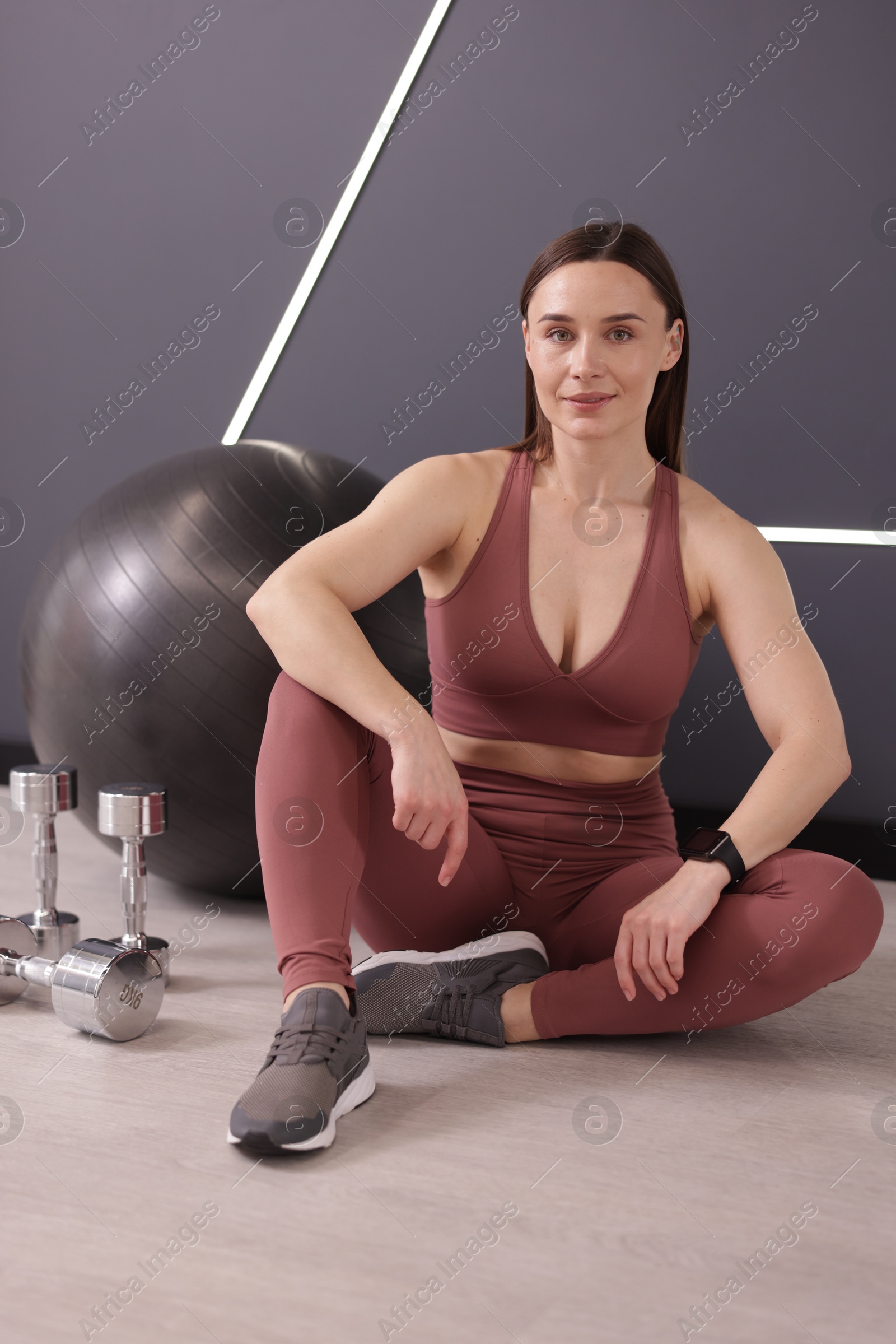 Photo of Woman with different gym equipment on floor in fitness studio