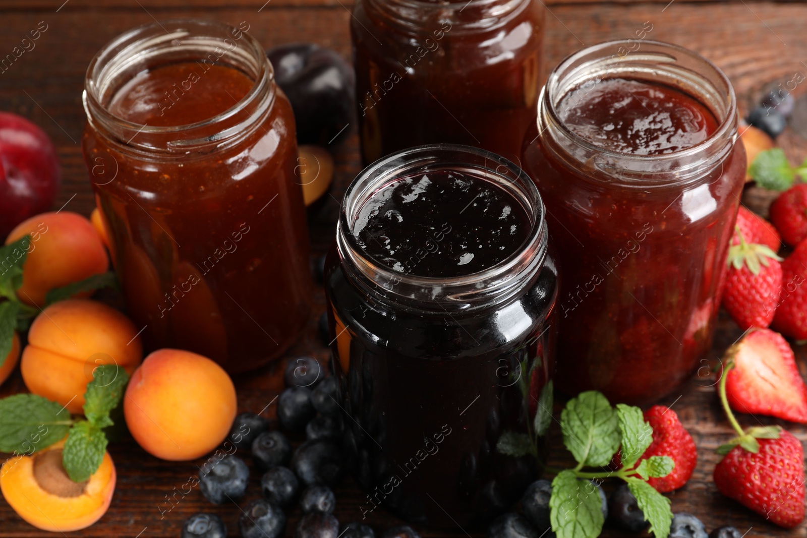 Different jams in jars and ingredients on wooden table, closeup Photo of Different jams in jars and ingredients on wooden table, closeup