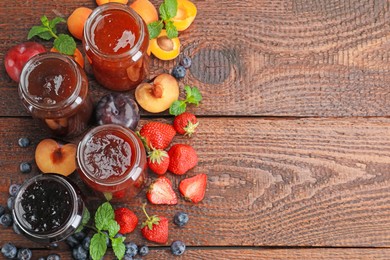 Photo of Different jams in jars and ingredients on wooden table, flat lay. Space for text