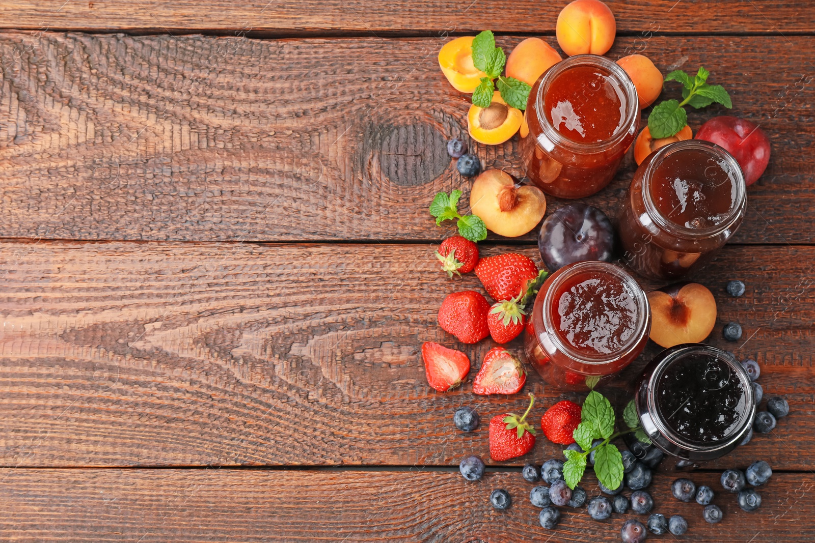 Different jams in jars and ingredients on wooden table, flat lay. Space for text Photo of Different jams in jars and ingredients on wooden table, flat lay. Space for text