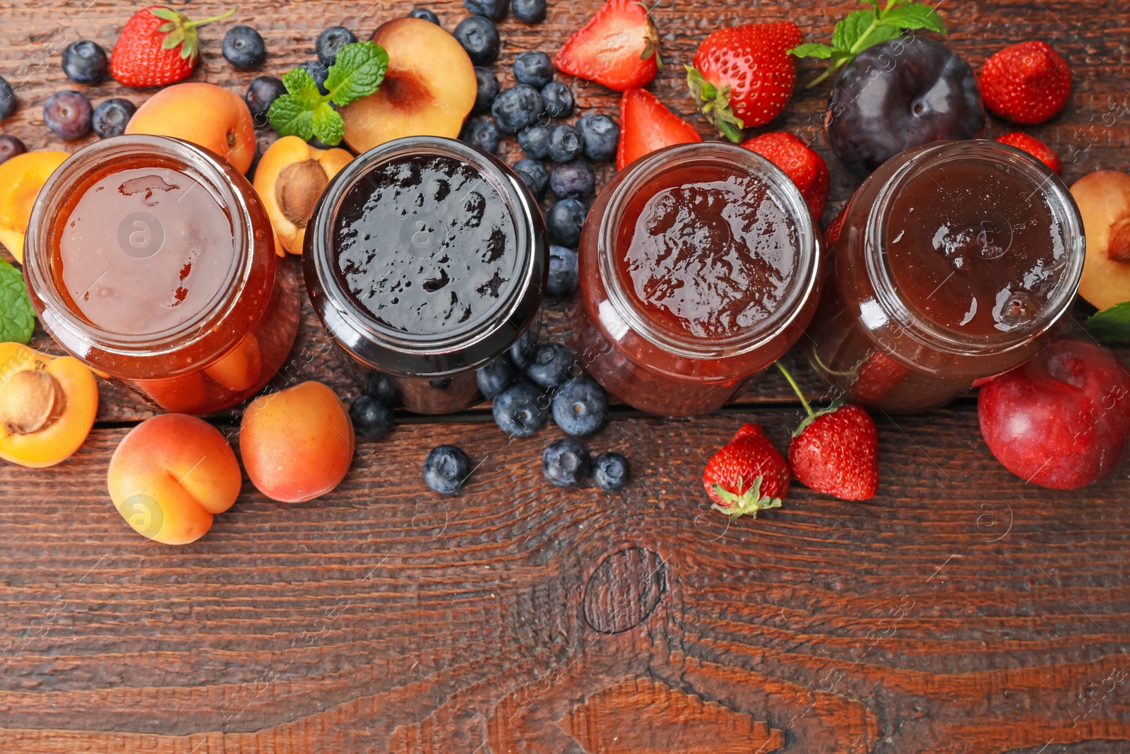 Different jams in jars and ingredients on wooden table, flat lay. Space for text Photo of Different jams in jars and ingredients on wooden table, flat lay. Space for text