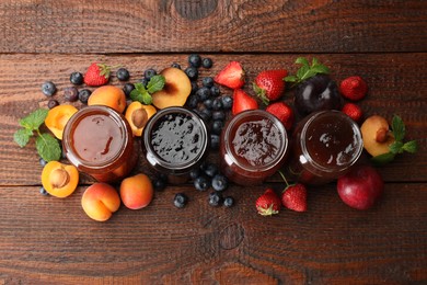 Photo of Different jams in jars and ingredients on wooden table, flat lay