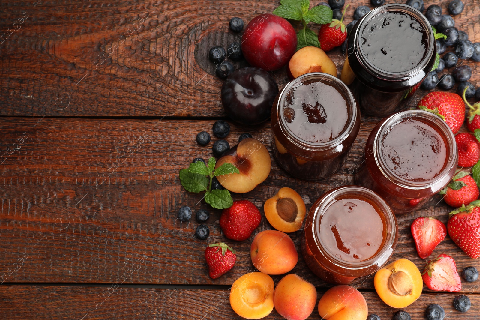 Different jams in jars and ingredients on wooden table, flat lay. Space for text Photo of Different jams in jars and ingredients on wooden table, flat lay. Space for text