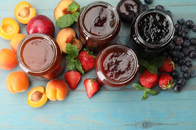 Photo of Different jams in jars and ingredients on blue wooden table, flat lay