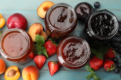 Photo of Different jams in jars and ingredients on blue wooden table, flat lay