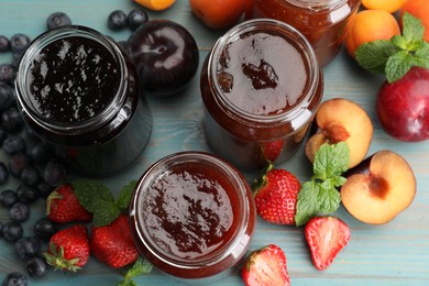 Photo of Different jams in jars and ingredients on blue wooden table, flat lay