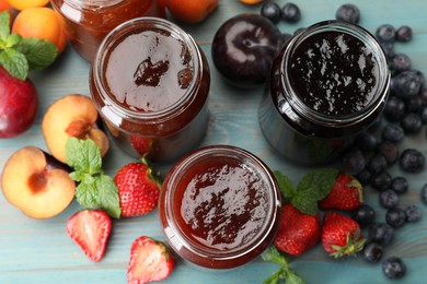 Photo of Different jams in jars and ingredients on blue wooden table, flat lay