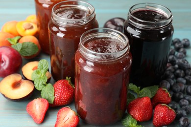 Photo of Different jams in jars and ingredients on blue wooden table, closeup