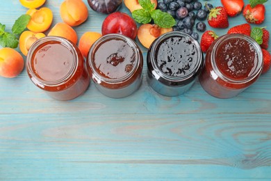 Photo of Different jams in jars and ingredients on blue wooden table, flat lay. Space for text