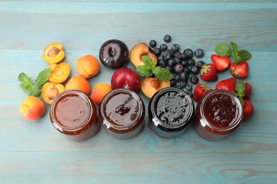 Photo of Different jams in jars and ingredients on blue wooden table, flat lay