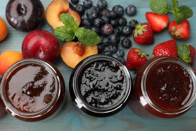 Photo of Different jams in jars and ingredients on blue wooden table, flat lay