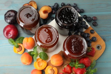 Photo of Different jams in jars and ingredients on blue wooden table, flat lay