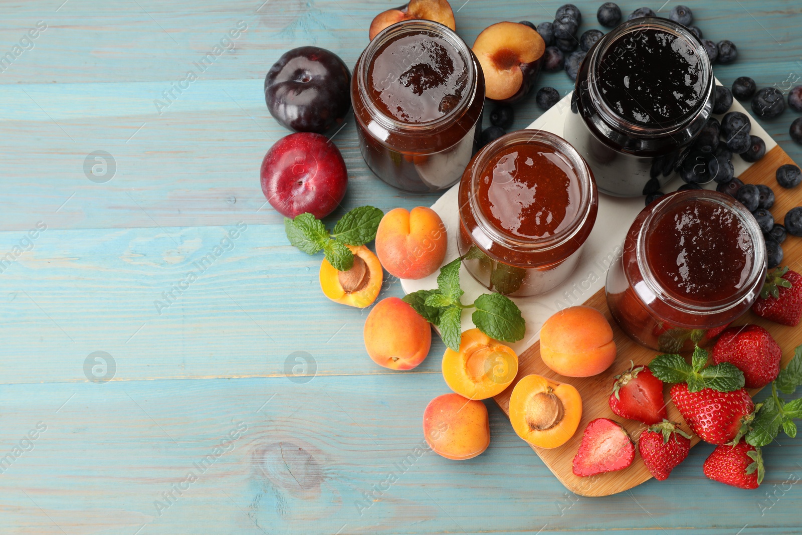 Different jams in jars and ingredients on blue wooden table, flat lay. Space for text Photo of Different jams in jars and ingredients on blue wooden table, flat lay. Space for text
