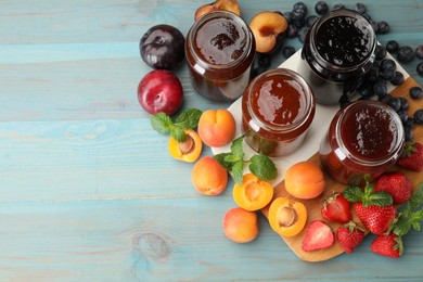 Photo of Different jams in jars and ingredients on blue wooden table, flat lay. Space for text