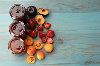 Photo of Different jams in jars and ingredients on blue wooden table, flat lay. Space for text