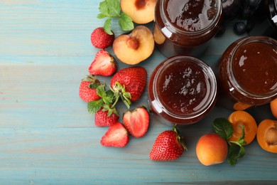 Photo of Different jams in jars and ingredients on blue wooden table, flat lay. Space for text