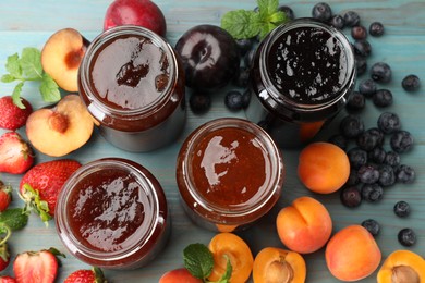 Photo of Different jams in jars and ingredients on blue wooden table, flat lay