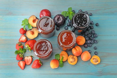 Photo of Different jams in jars and ingredients on blue wooden table, flat lay