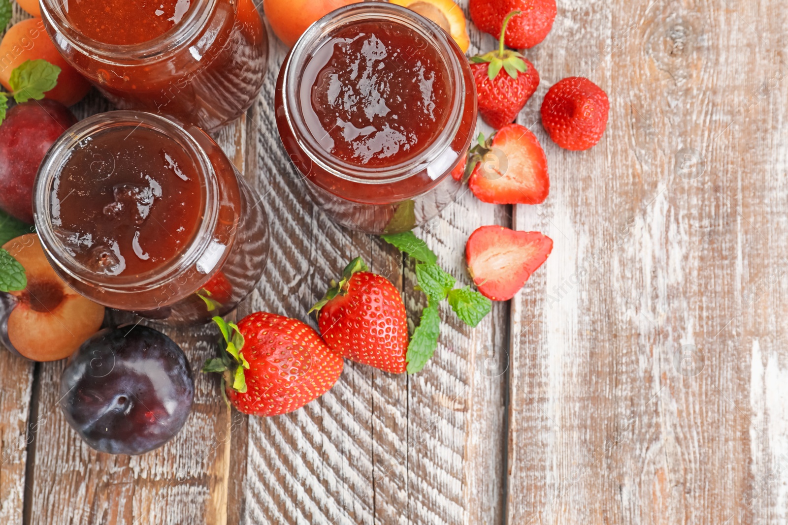 Different jams in jars and ingredients on wooden table, flat lay. Space for text Photo of Different jams in jars and ingredients on wooden table, flat lay. Space for text