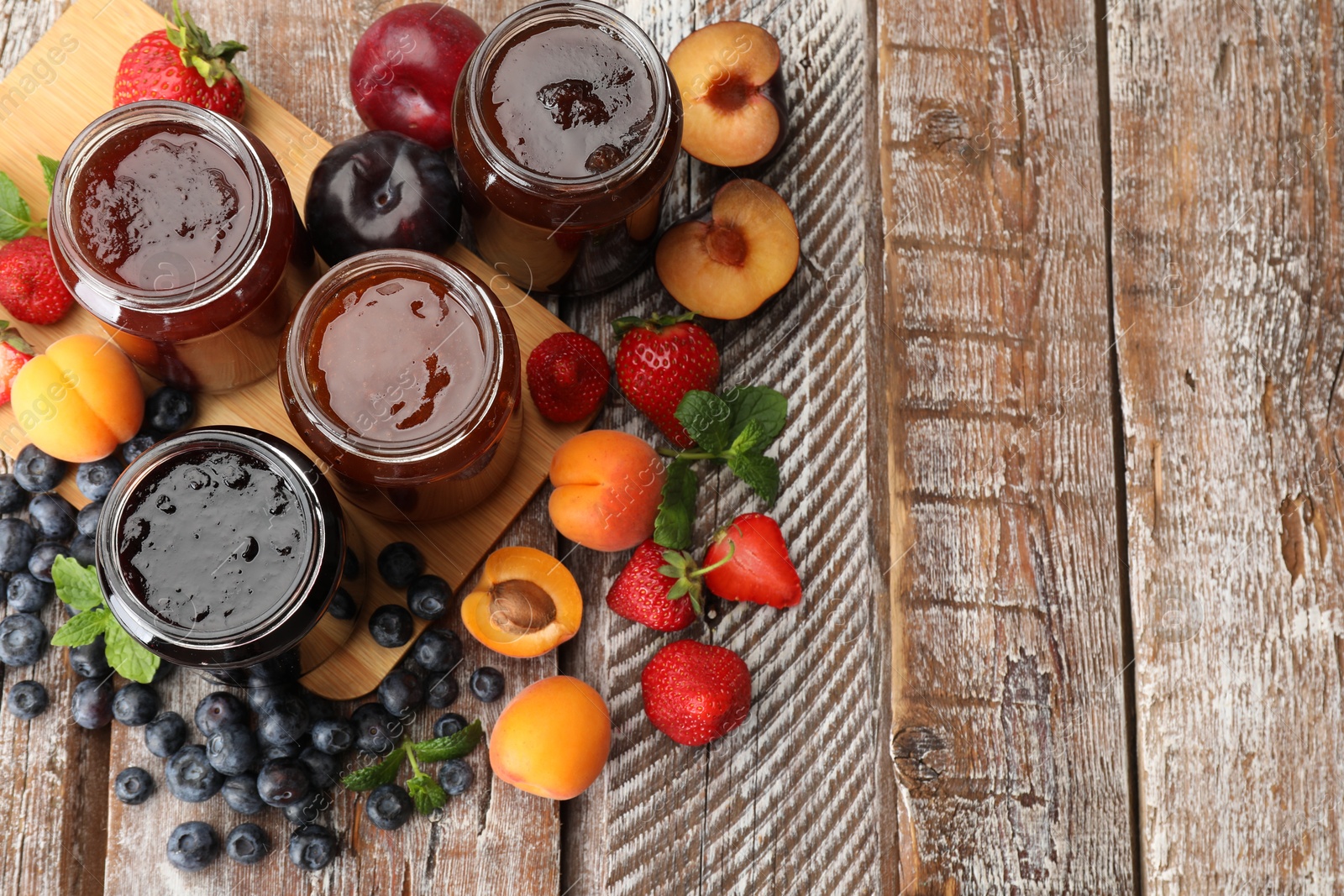 Different jams in jars and ingredients on wooden table, flat lay. Space for text Photo of Different jams in jars and ingredients on wooden table, flat lay. Space for text