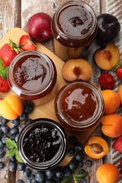 Photo of Different jams in jars and ingredients on wooden table, flat lay